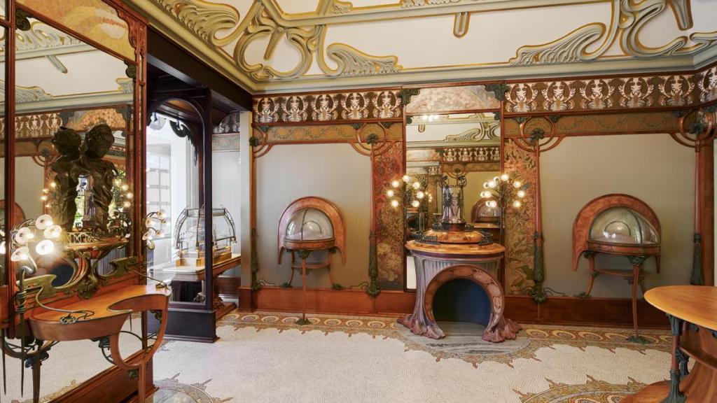 Elaborate gold, glass and polished wood parlour completely fitted out in Art Nouveau style, with swirling green lamps and curved wood furniture